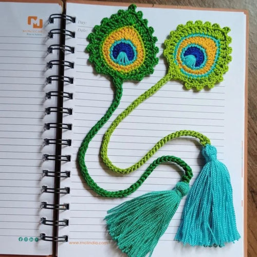Crocheted peacock feather bookmark with tassels on a notebook page